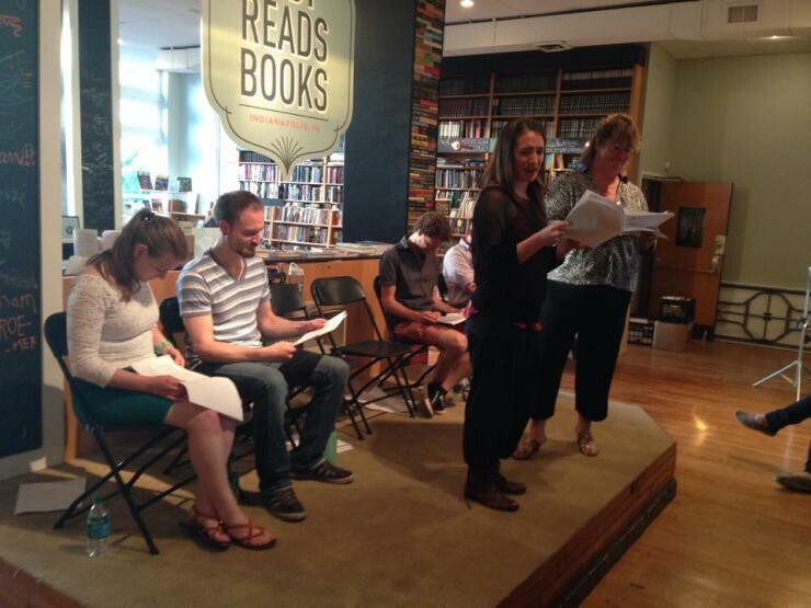 A group of people standing on a small stage in a bookstore.