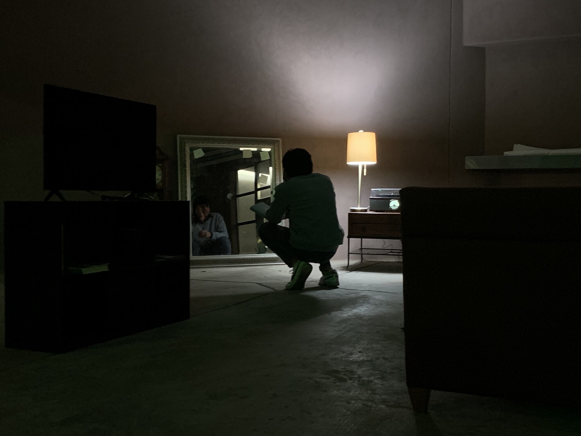 A dark room with a person crouching in the center.