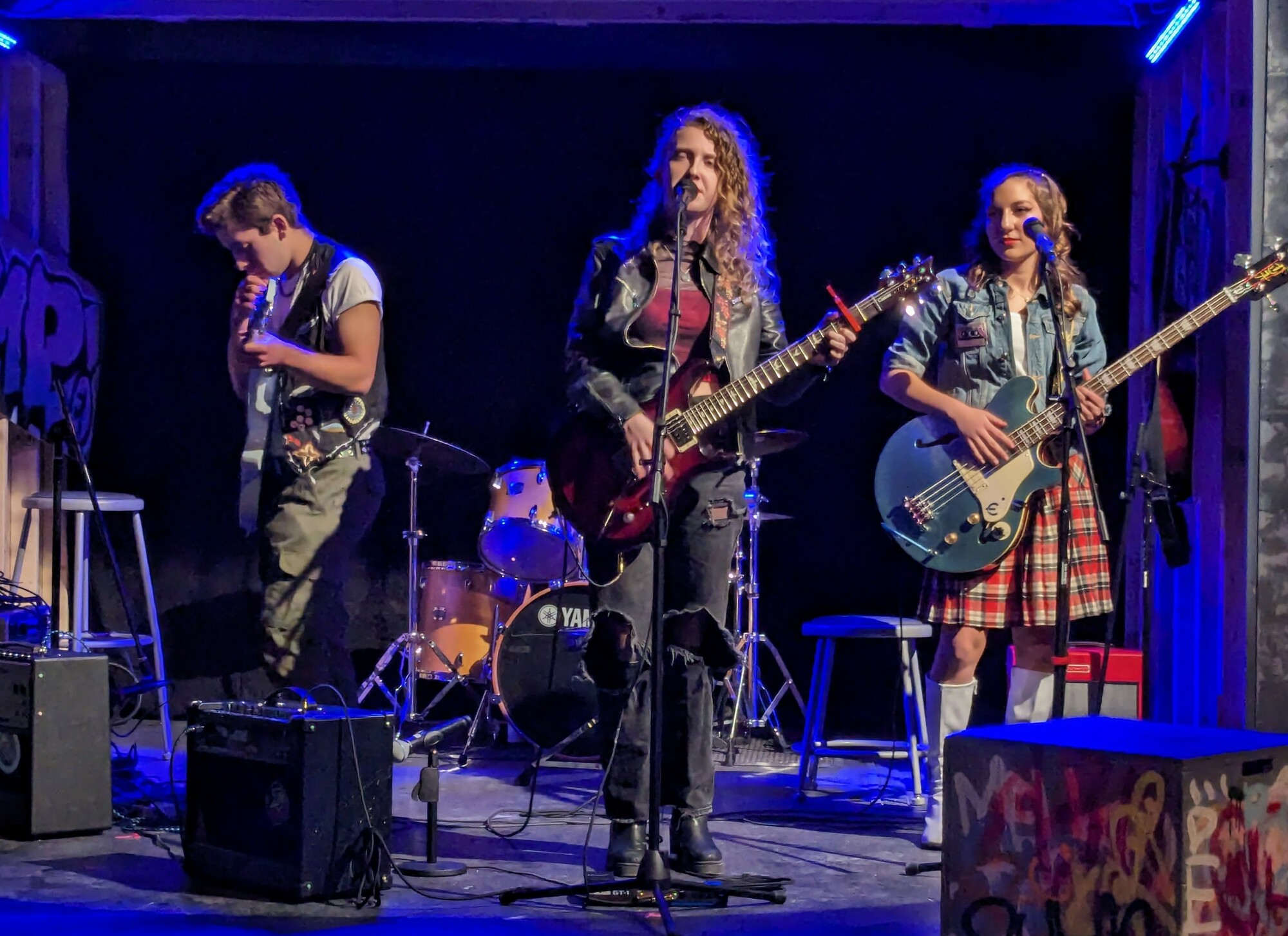 Three people in a rock band on stage. 