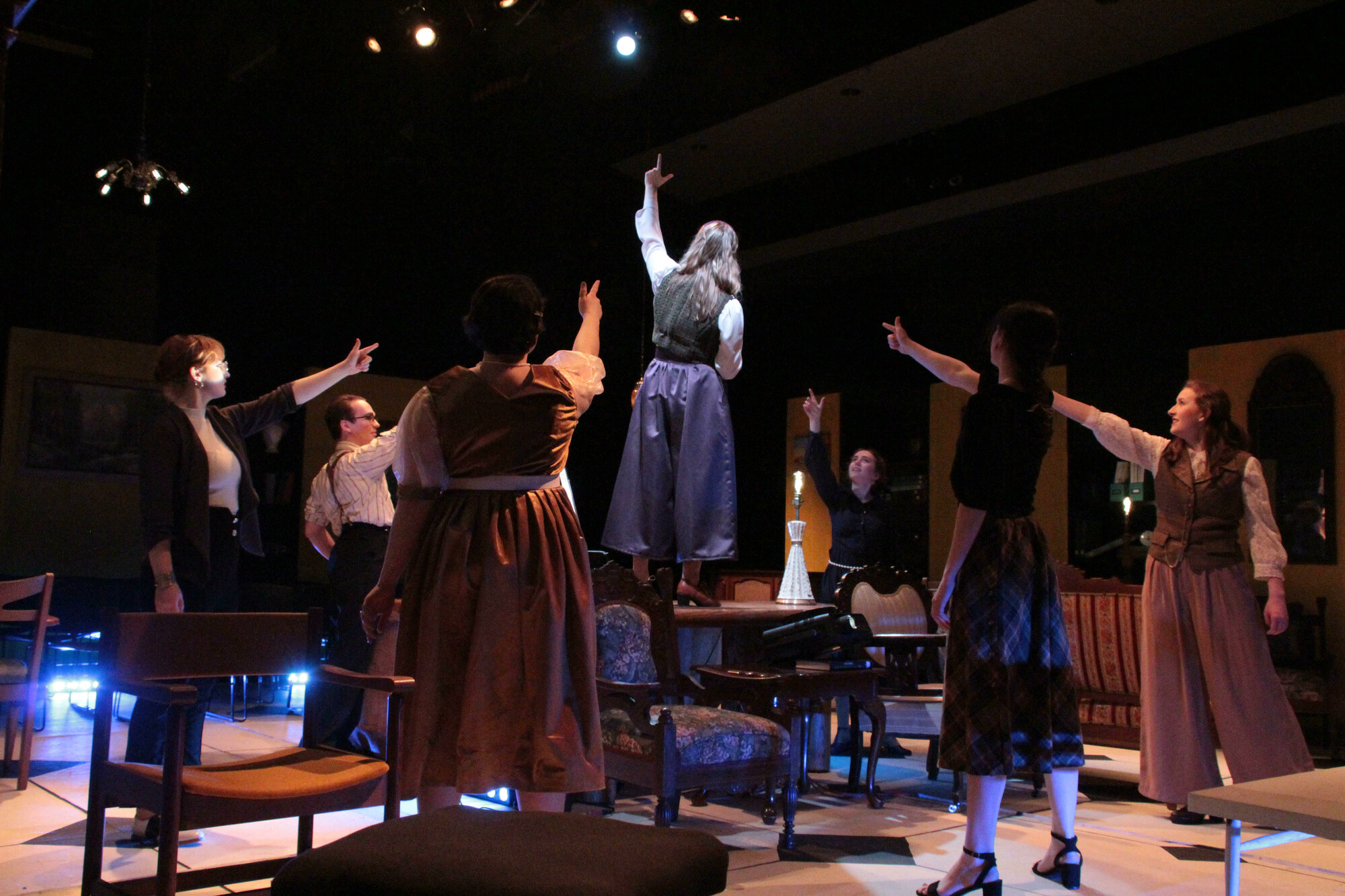 A group of people on stage gathered around another person standing on top of a table.