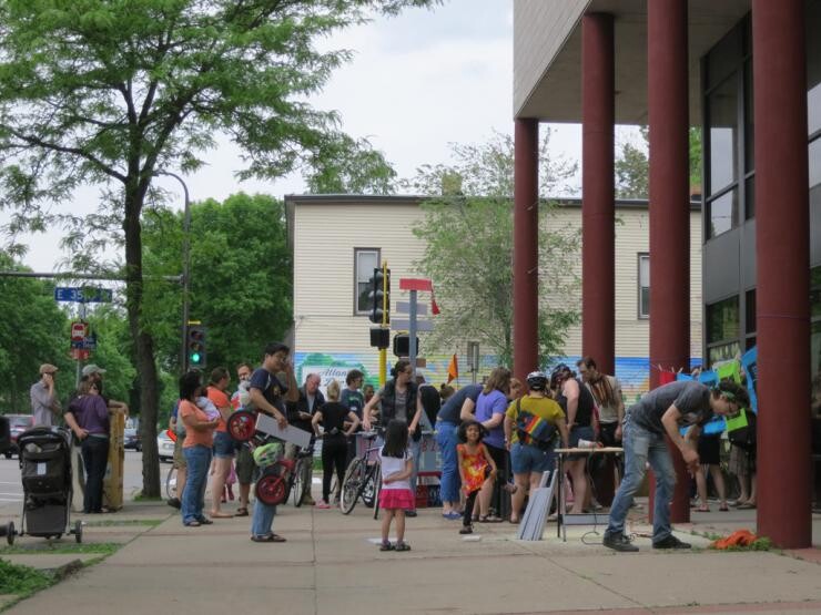 A crowd of people standing outside near a building.