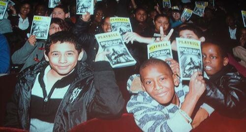Children holding up playbills.