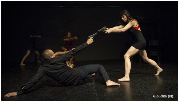 Two people on stage pointing guns at each other.