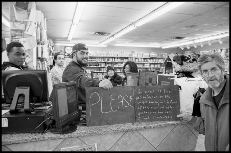 A black and white photo of people in a store holding signs.