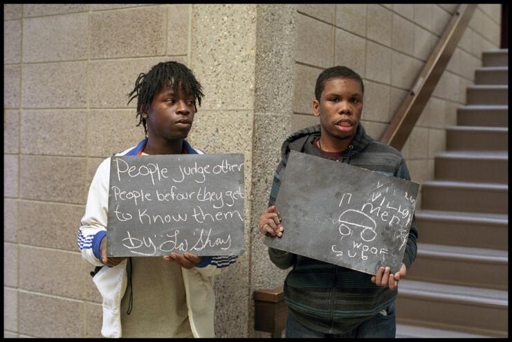 Two people holding small handwritten signs.