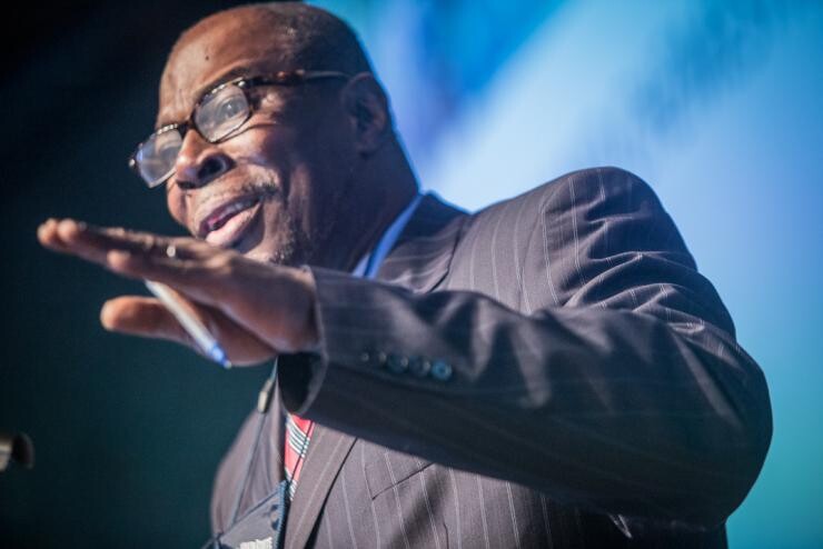 A Black man in a suit speaking passionately.