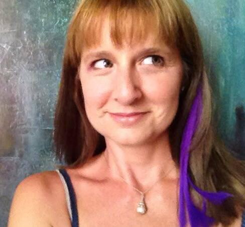 A red-head woman with a purple stripe taking a selfie.