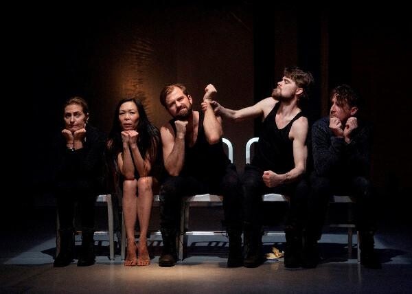 Five people sitting in chairs on stage.