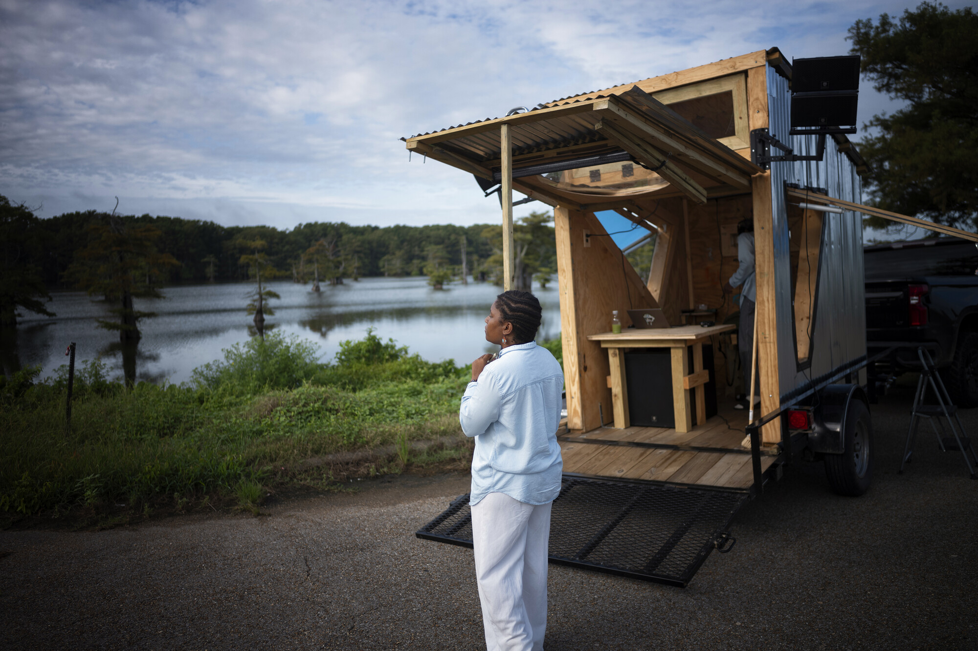 A person in all white standing near a tiny home.