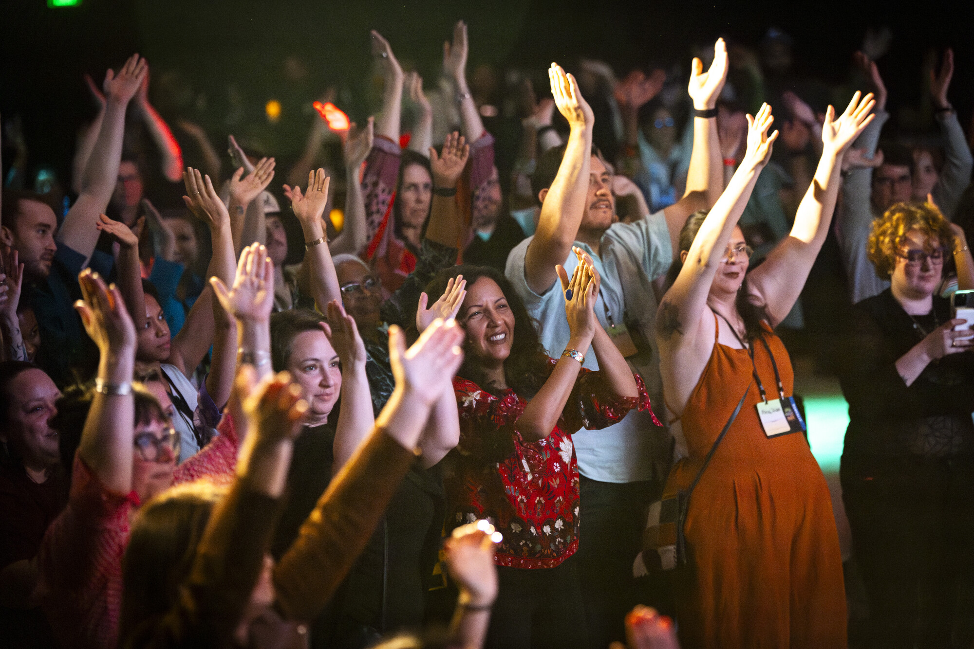 A crowd of people raising their hands and clapping.