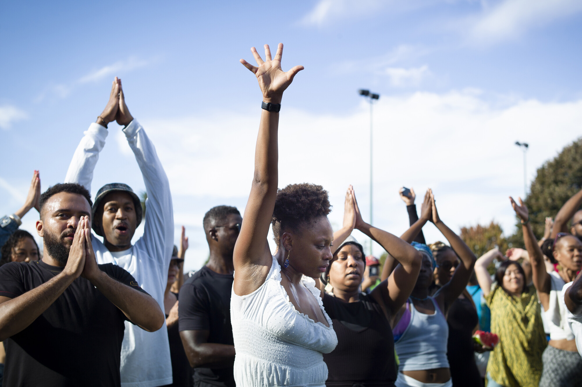 A woman in the middle of a crowd passionately reaching her hand upwards.