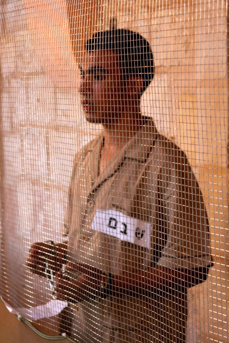 A man standing behind a wire screen.