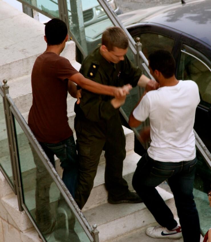 Two men struggling against a police officer.
