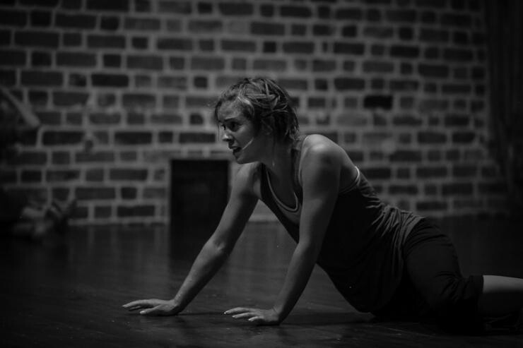 A black and white photo of a person on the ground propping themselves up with their arms.