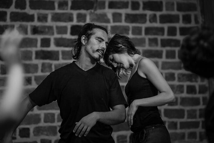 A black and white photo of a person resting their head on the should of another person.