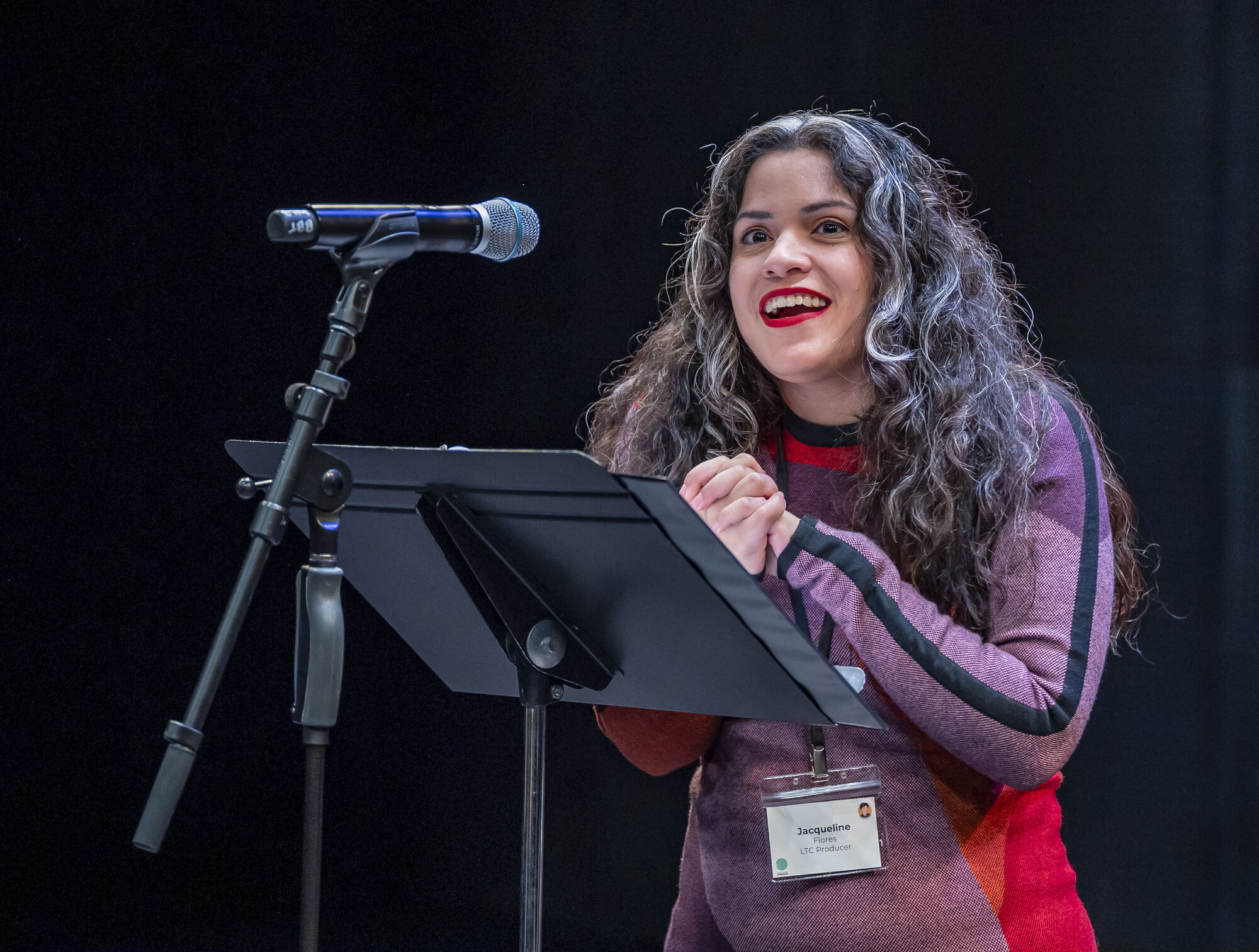 A woman standing behind a music stand and a microphone.