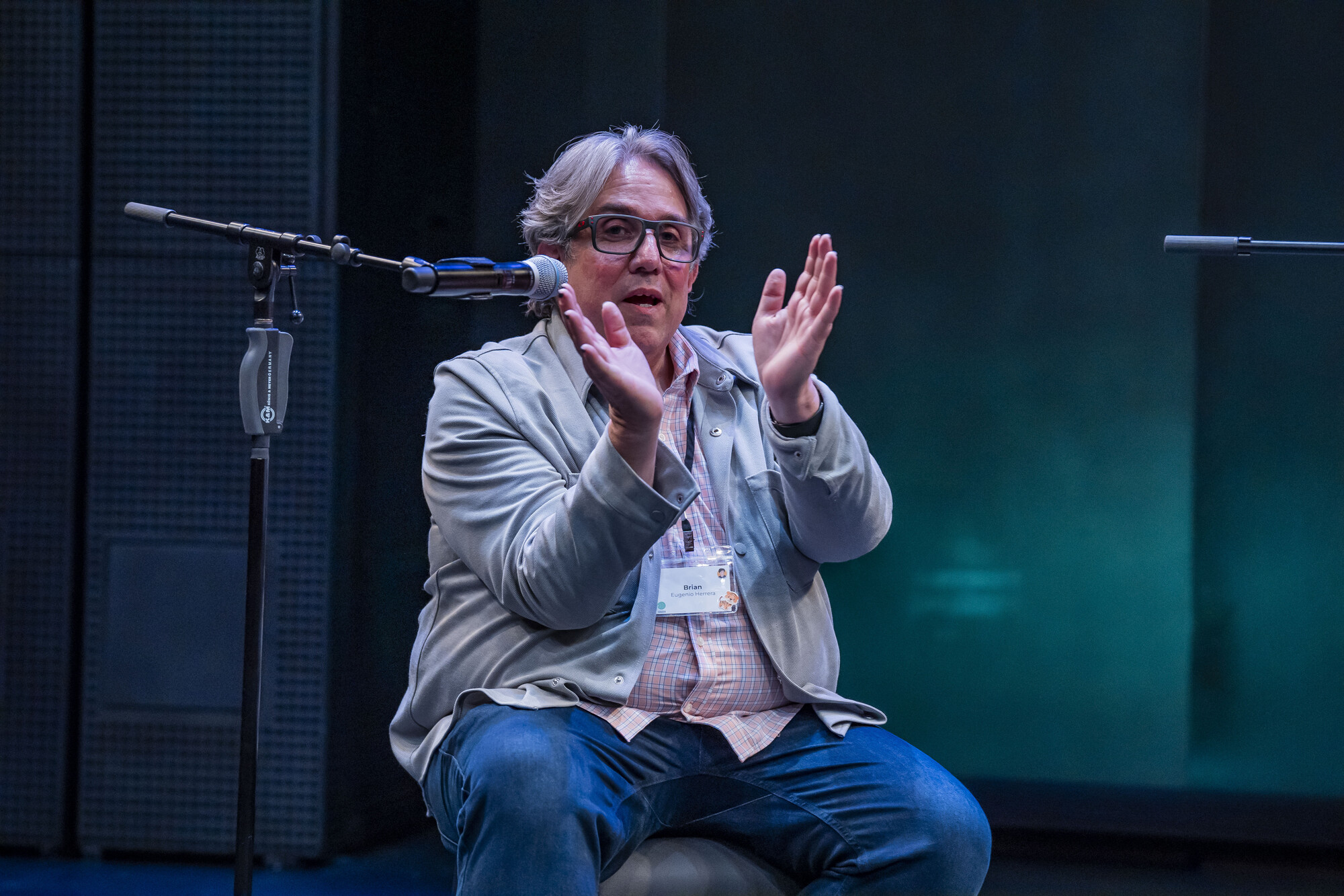 A man sitting on stage in front of a microphone.