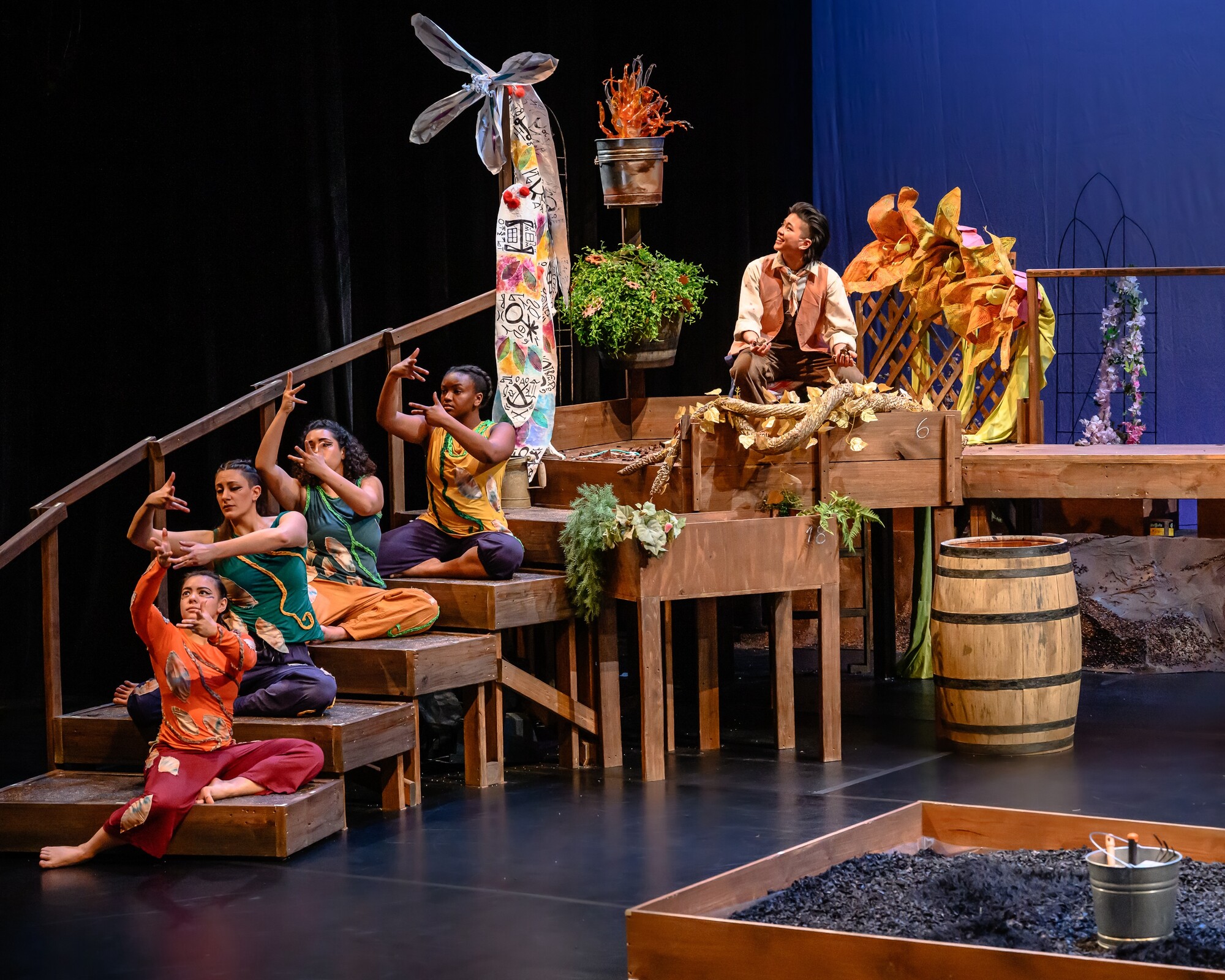 A colorful stair set on stage with actors in colorful clothes.