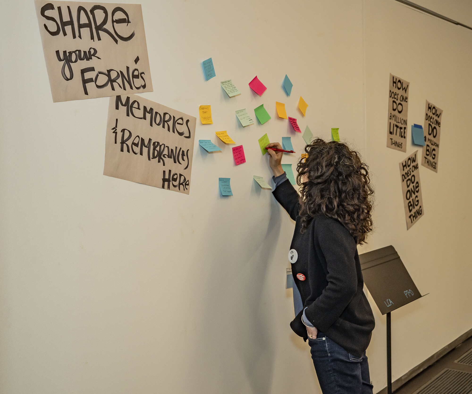 A person writing on a sticky note on the wall.