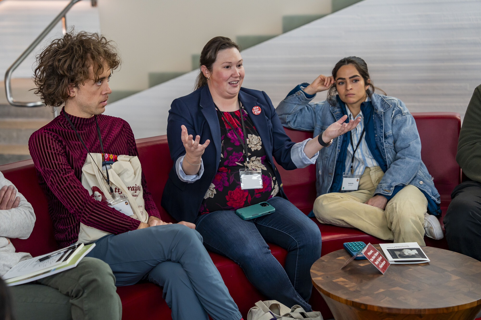 Three people sitting on a couch and talking.
