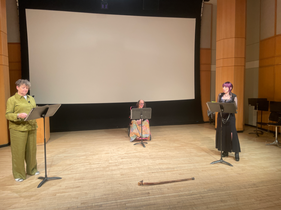 Three people on stage with black music stands.