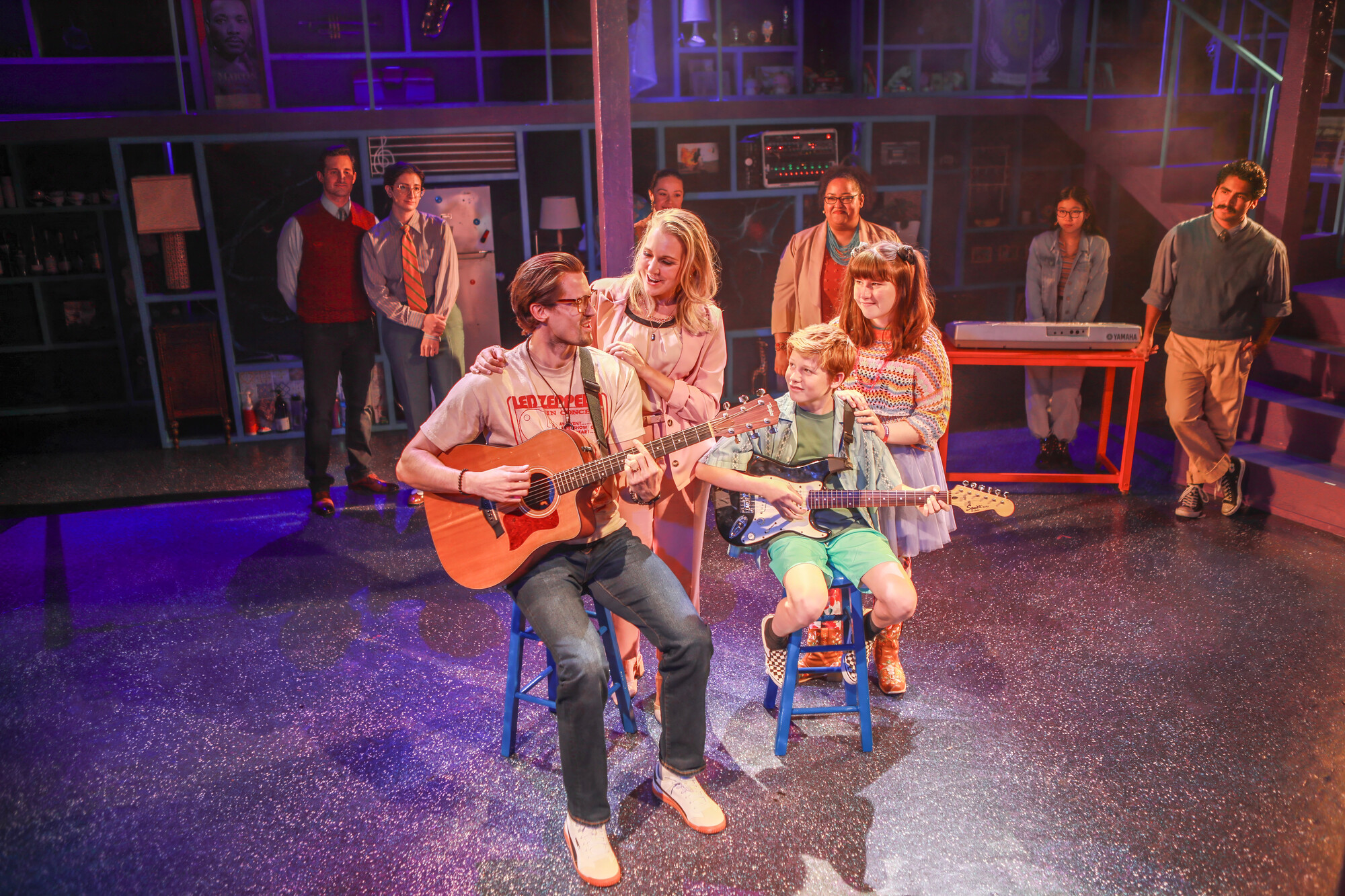 A group of actors on stage playing guitar.