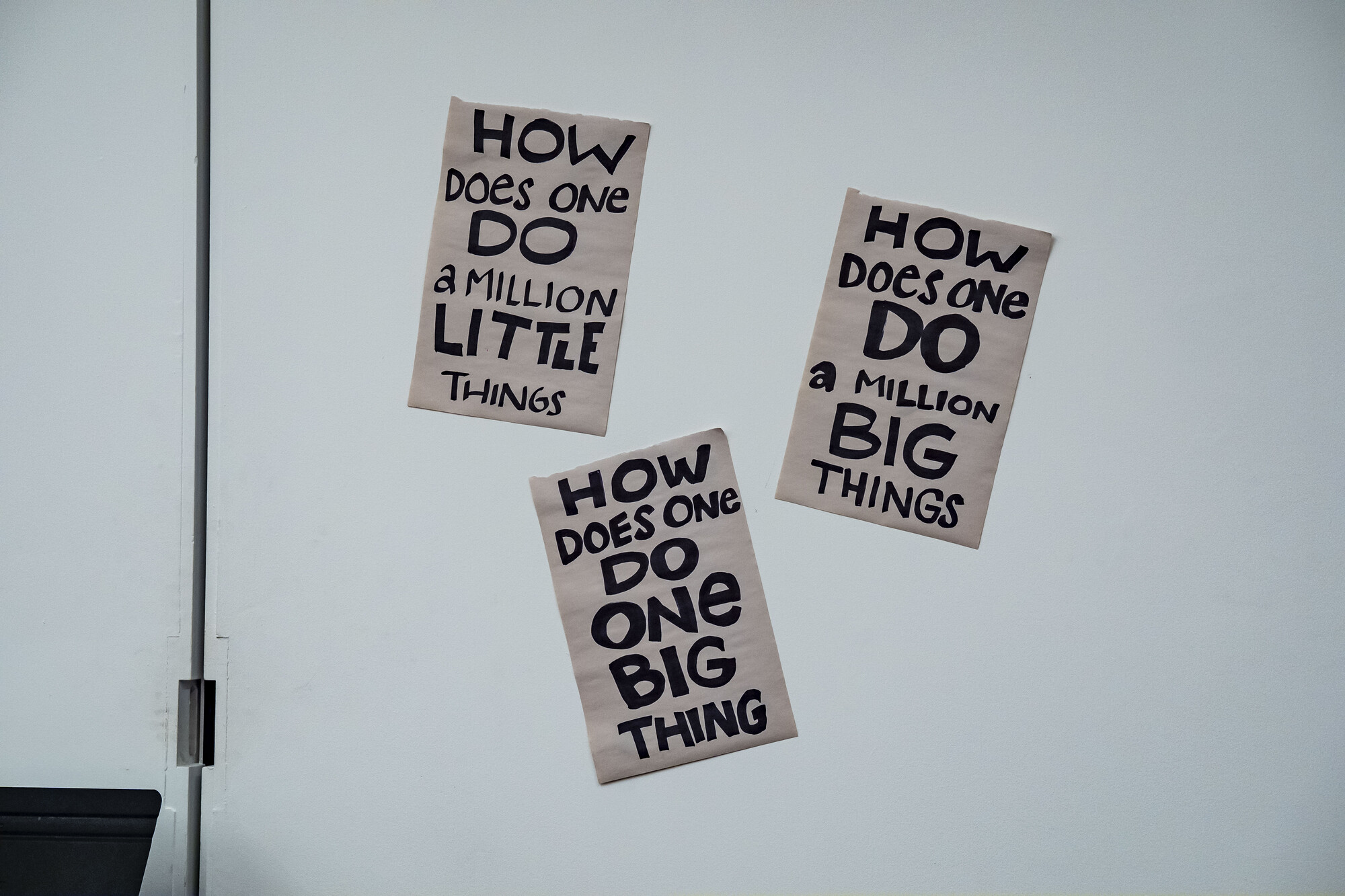 A wall with three signs on brown paper.