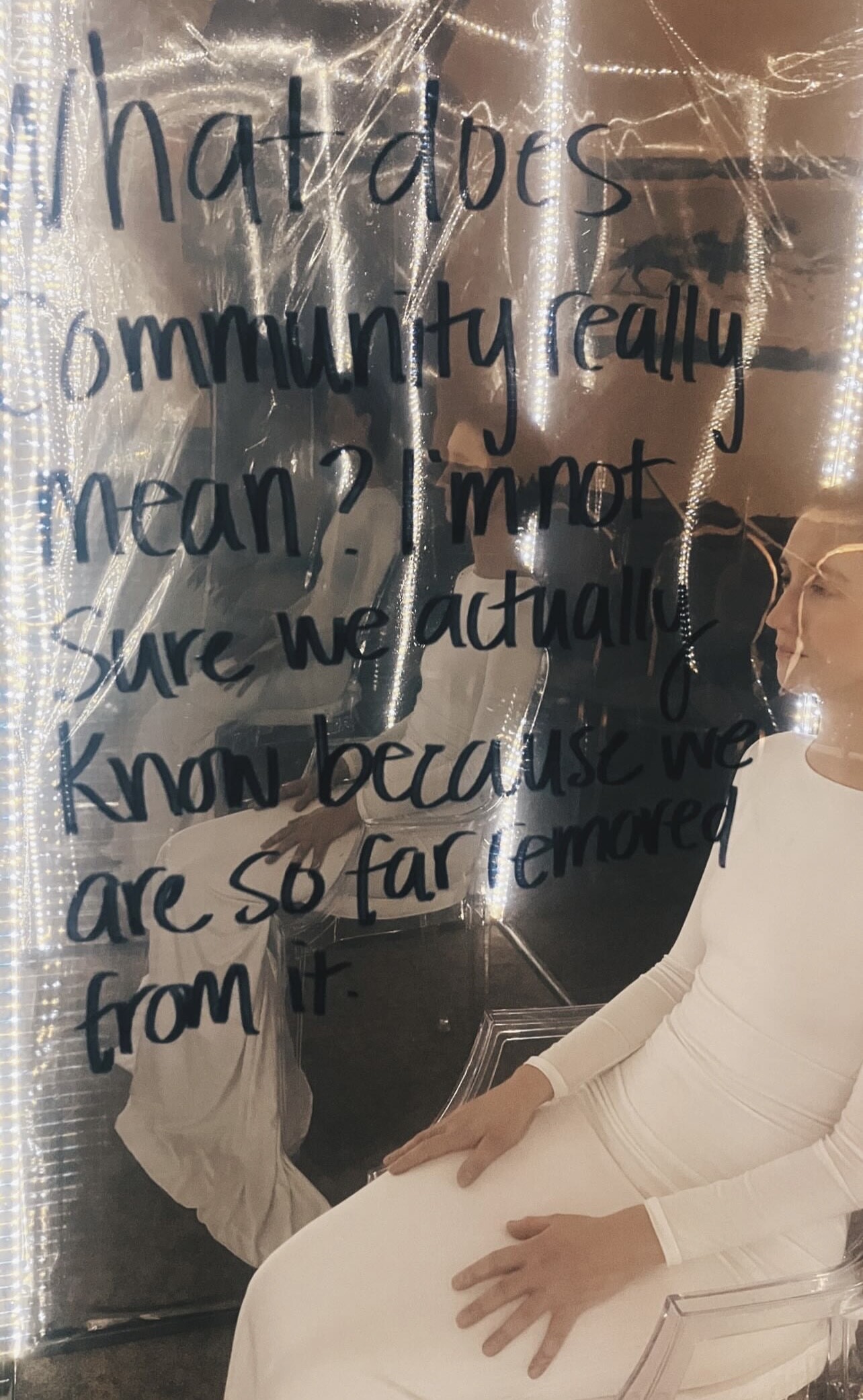A mirror with writing on it and a person dressed in white sitting nearby.