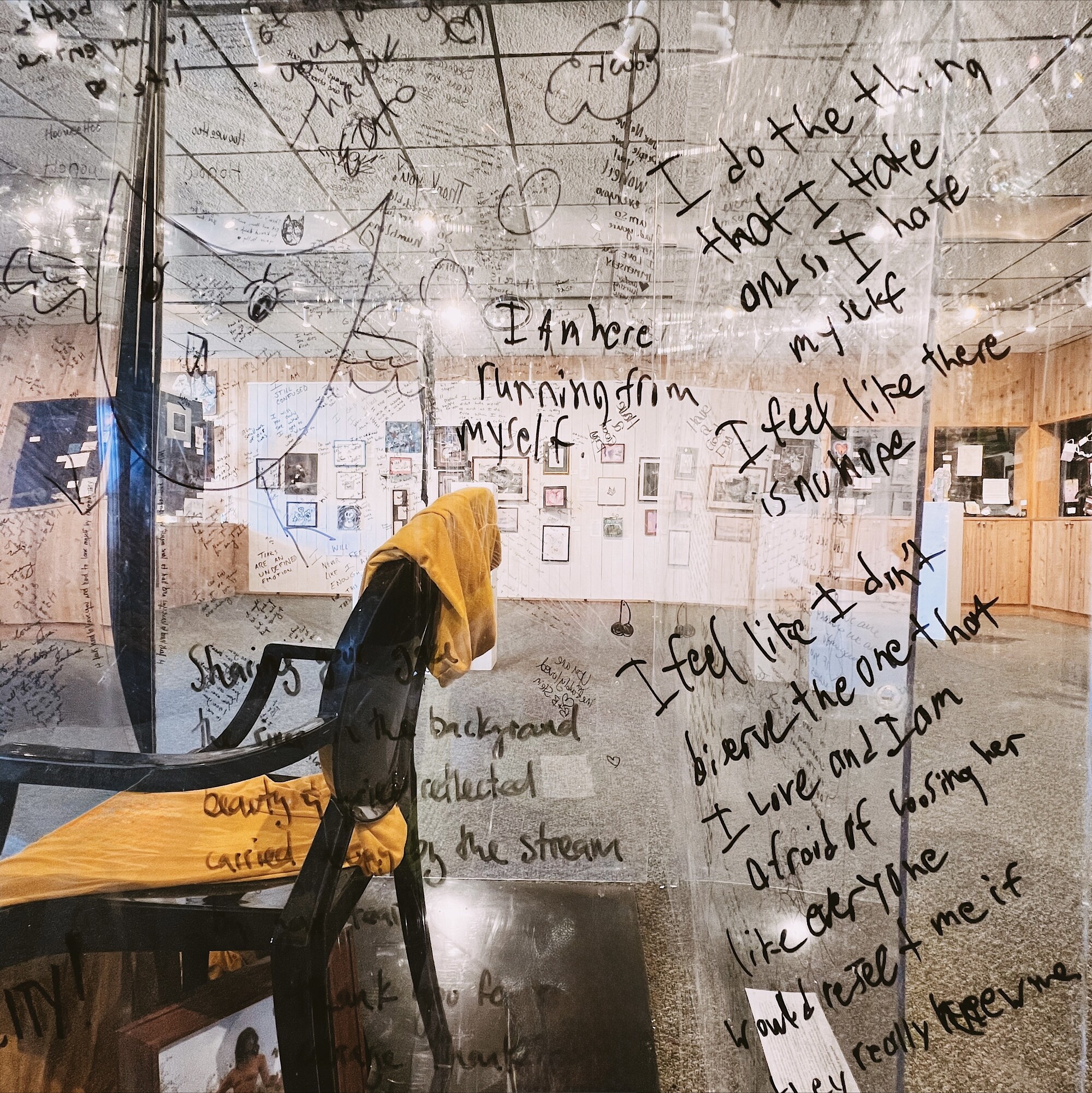 A glass box with writing on it and a chair in it.