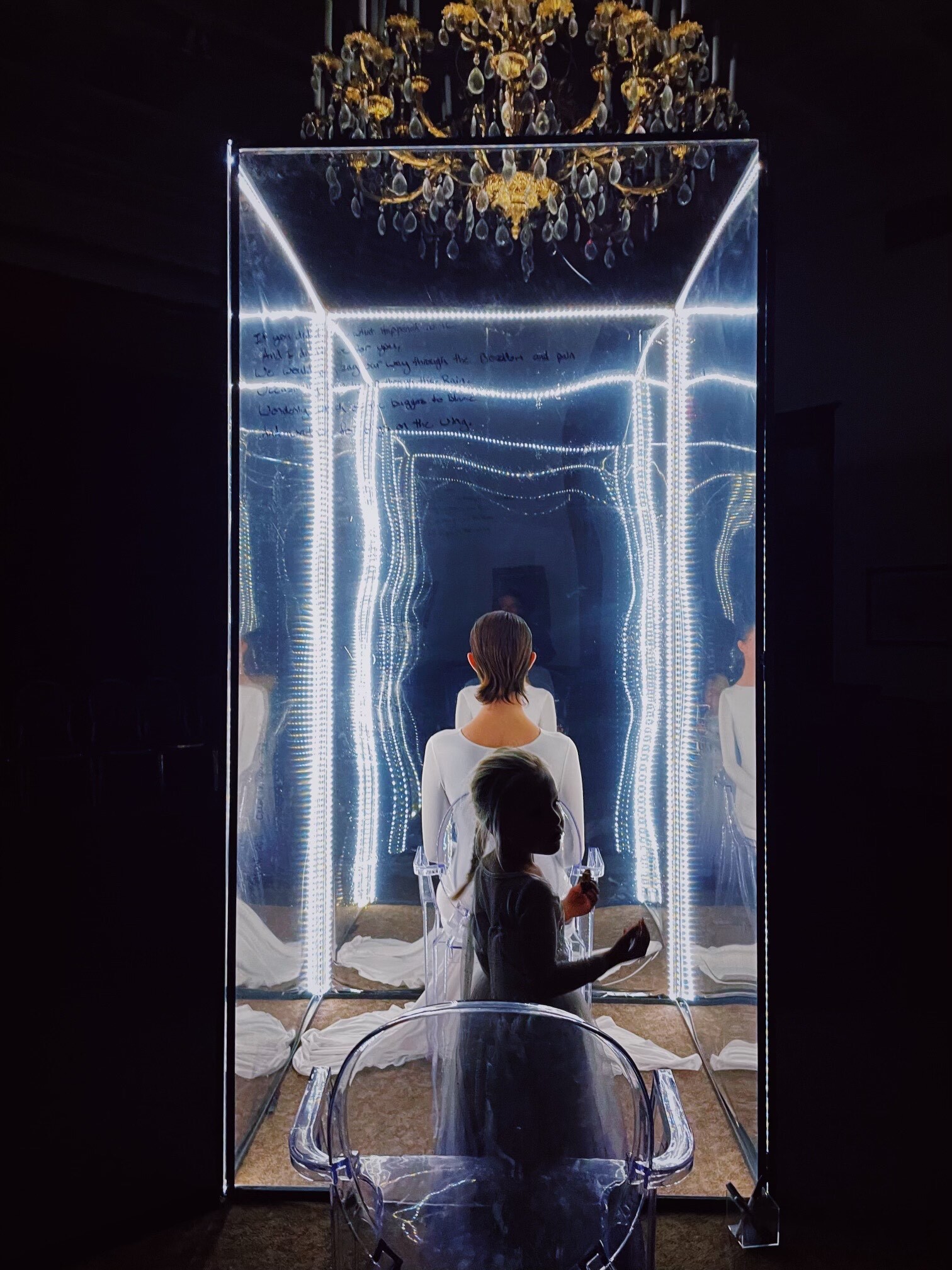 A mirror box with a person in white sitting inside.