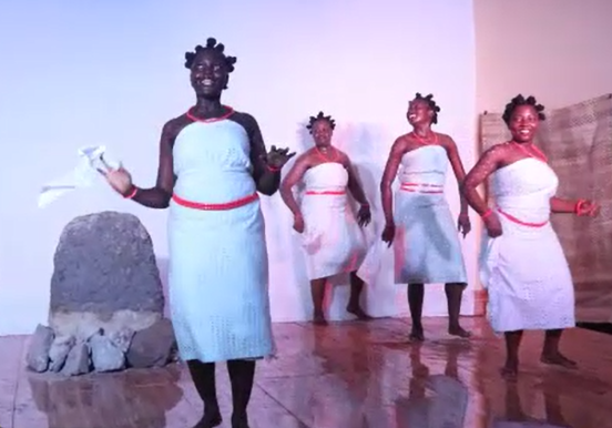 Four people in white cloth dresses on stage.