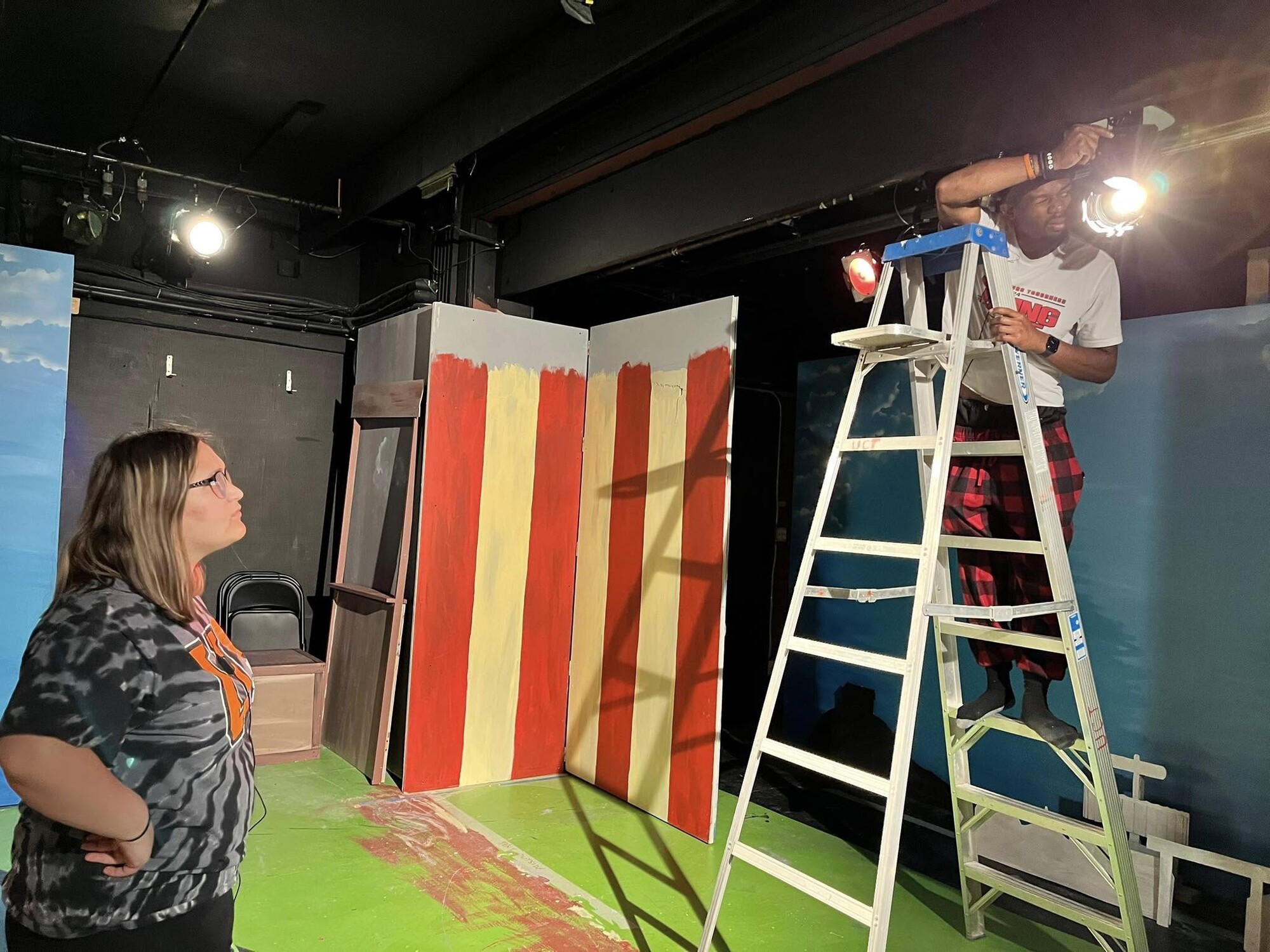 A person on a ladder and another person looking up at them.