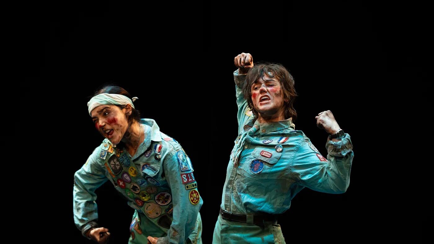 Two actors on stage in grimy costumes.