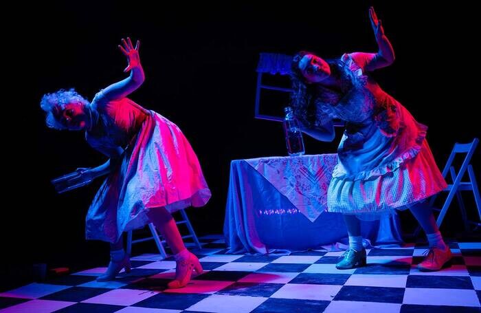 Two people dancing on a checkered floor in purple light.