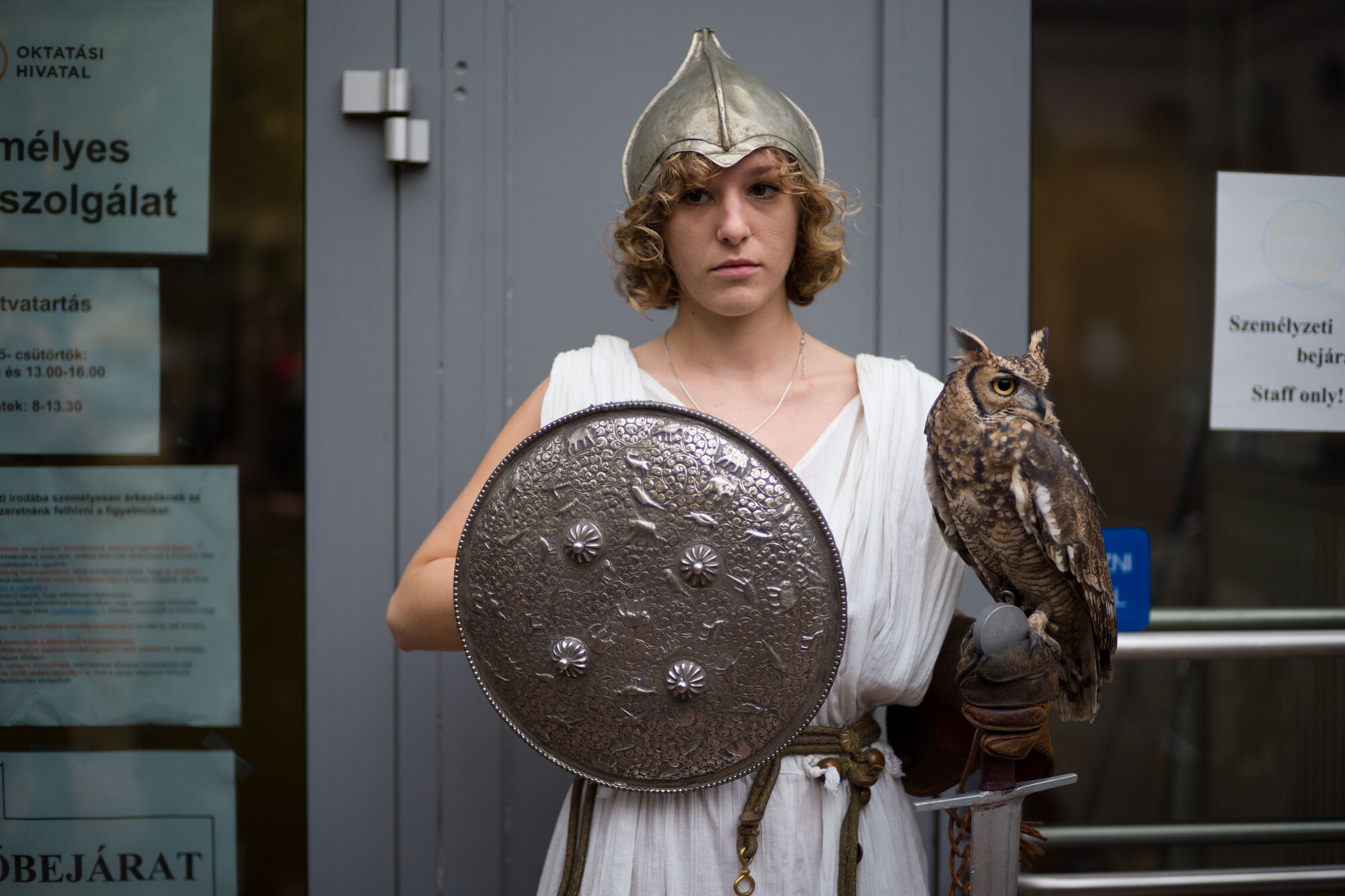 A person in a gladiator costume holding an owl and a shield.