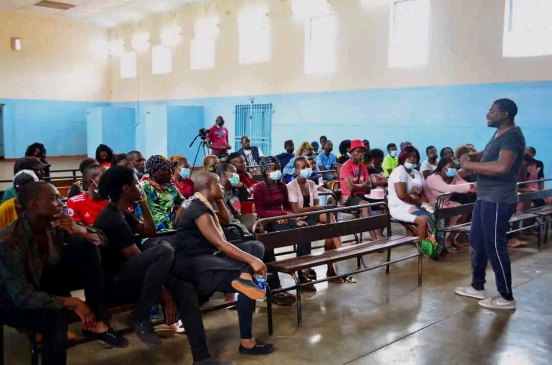 A group of people sitting on benches in an all purpose room.