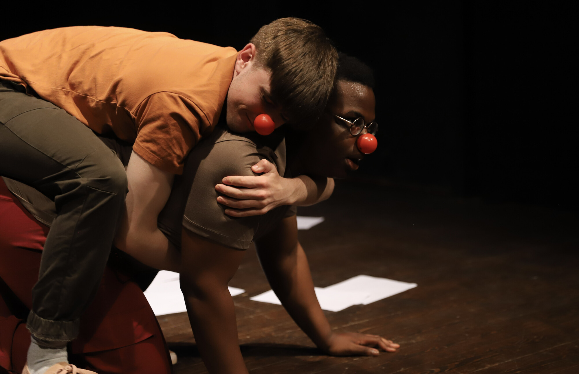Two people wrestling with clown noses on.