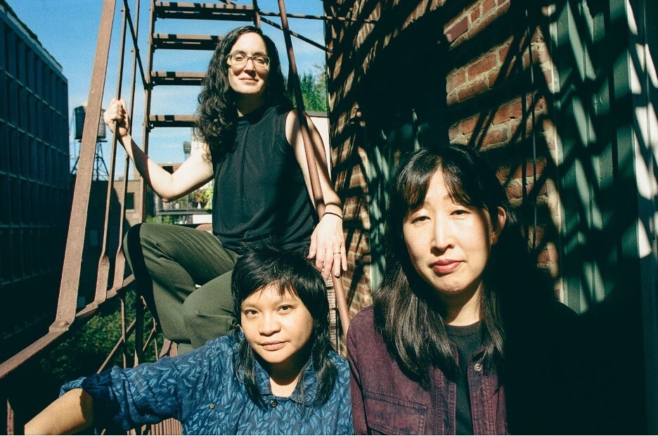 Three women posing together on a fire escape.