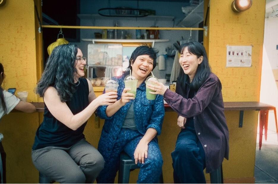 A group of three women posing with drinks in their hands.