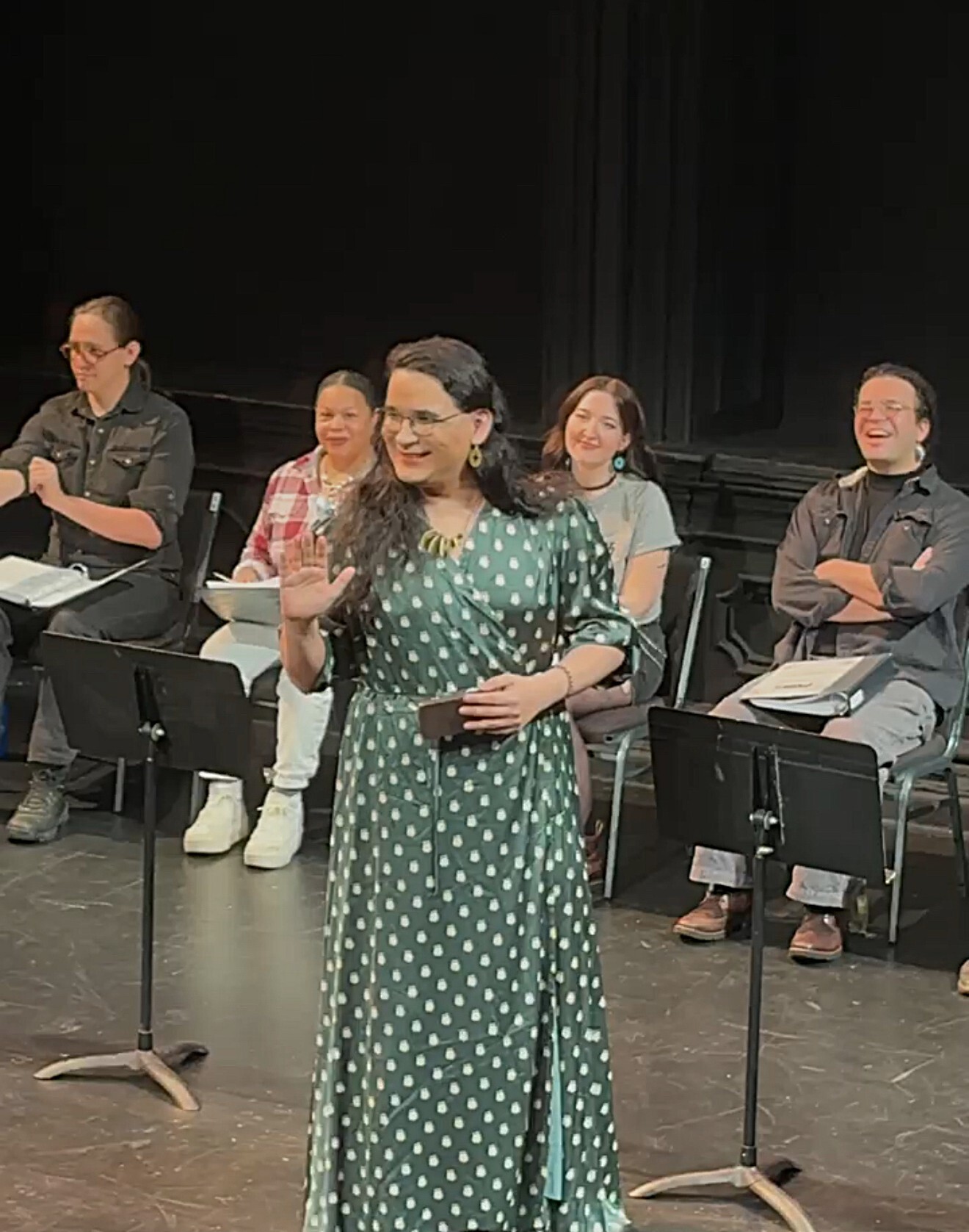 A woman in a green dress speaking on stage.