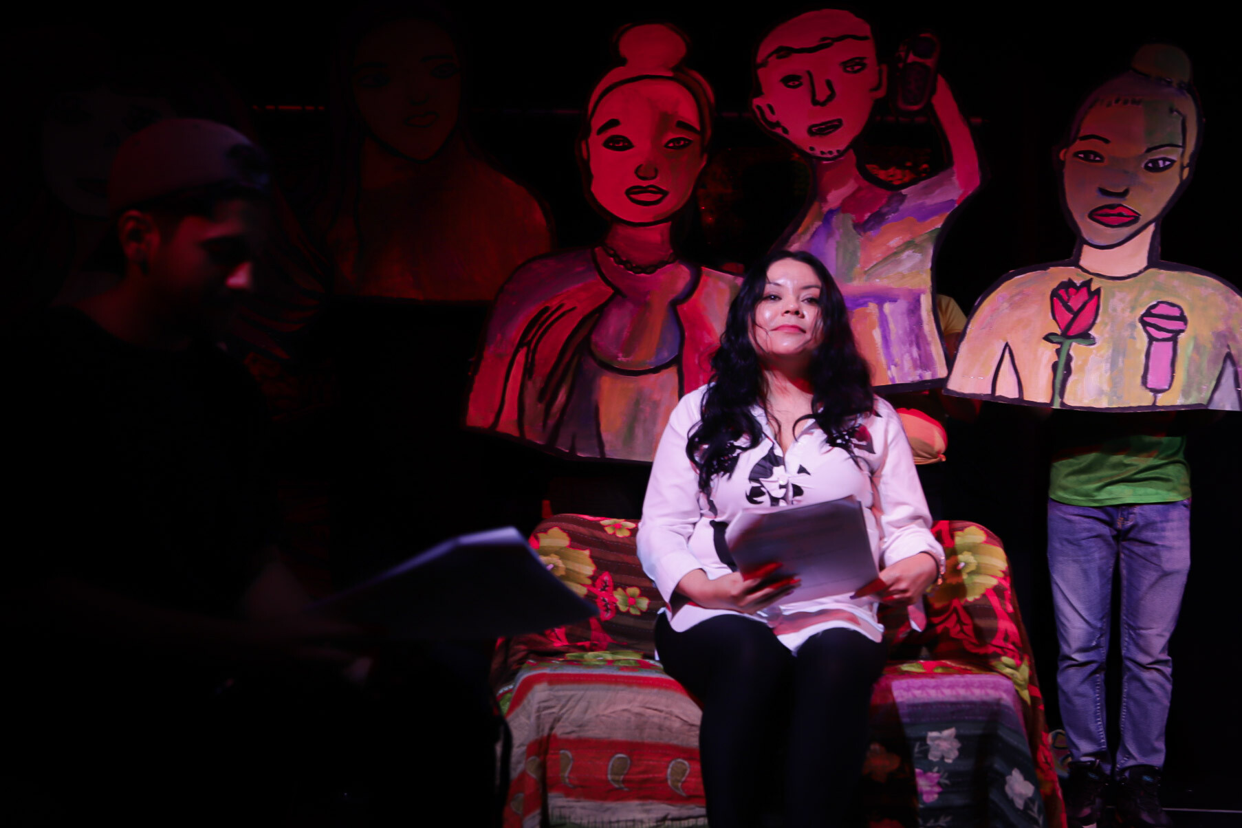 A person sitting in a chair with large puppets behind them.