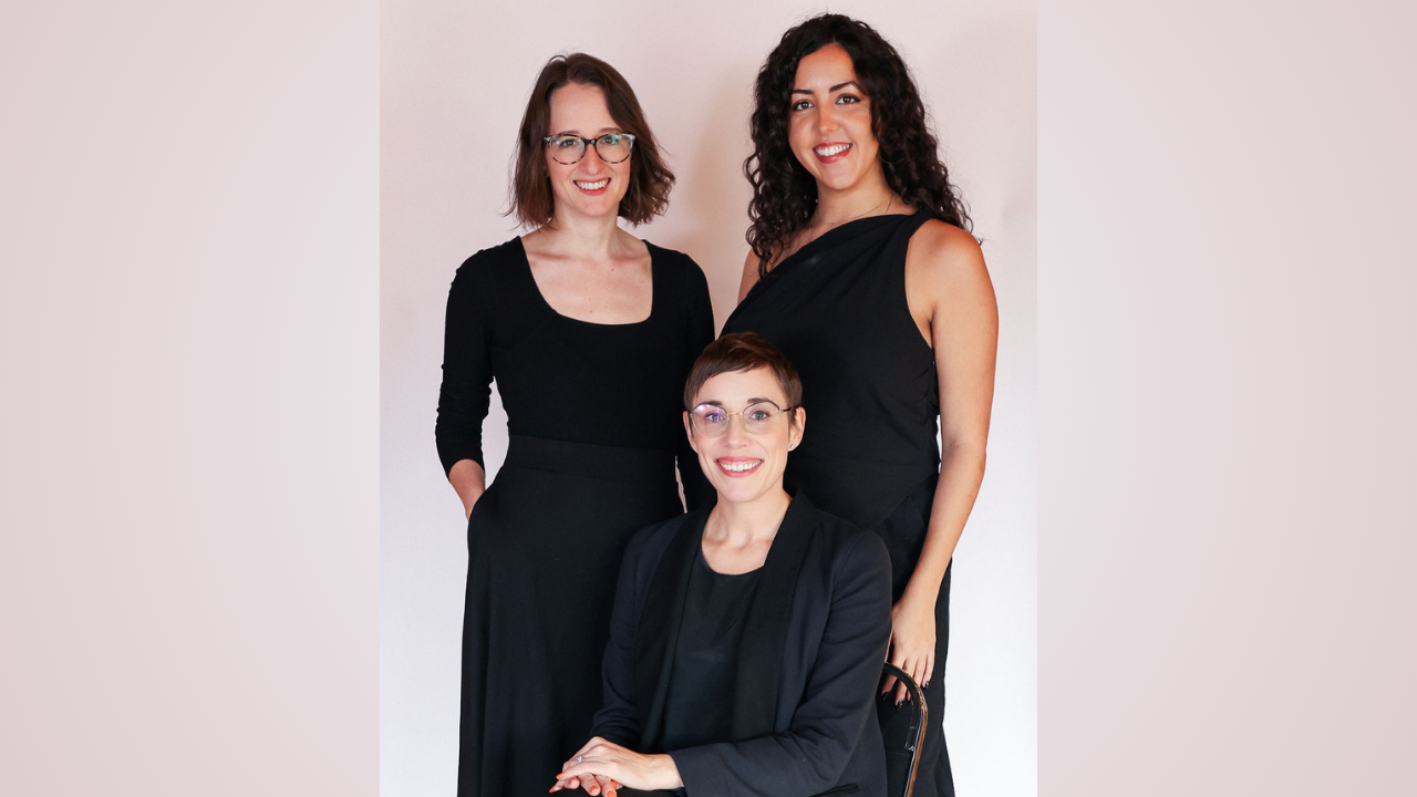 Three women dressed in all black posing for a photo together.