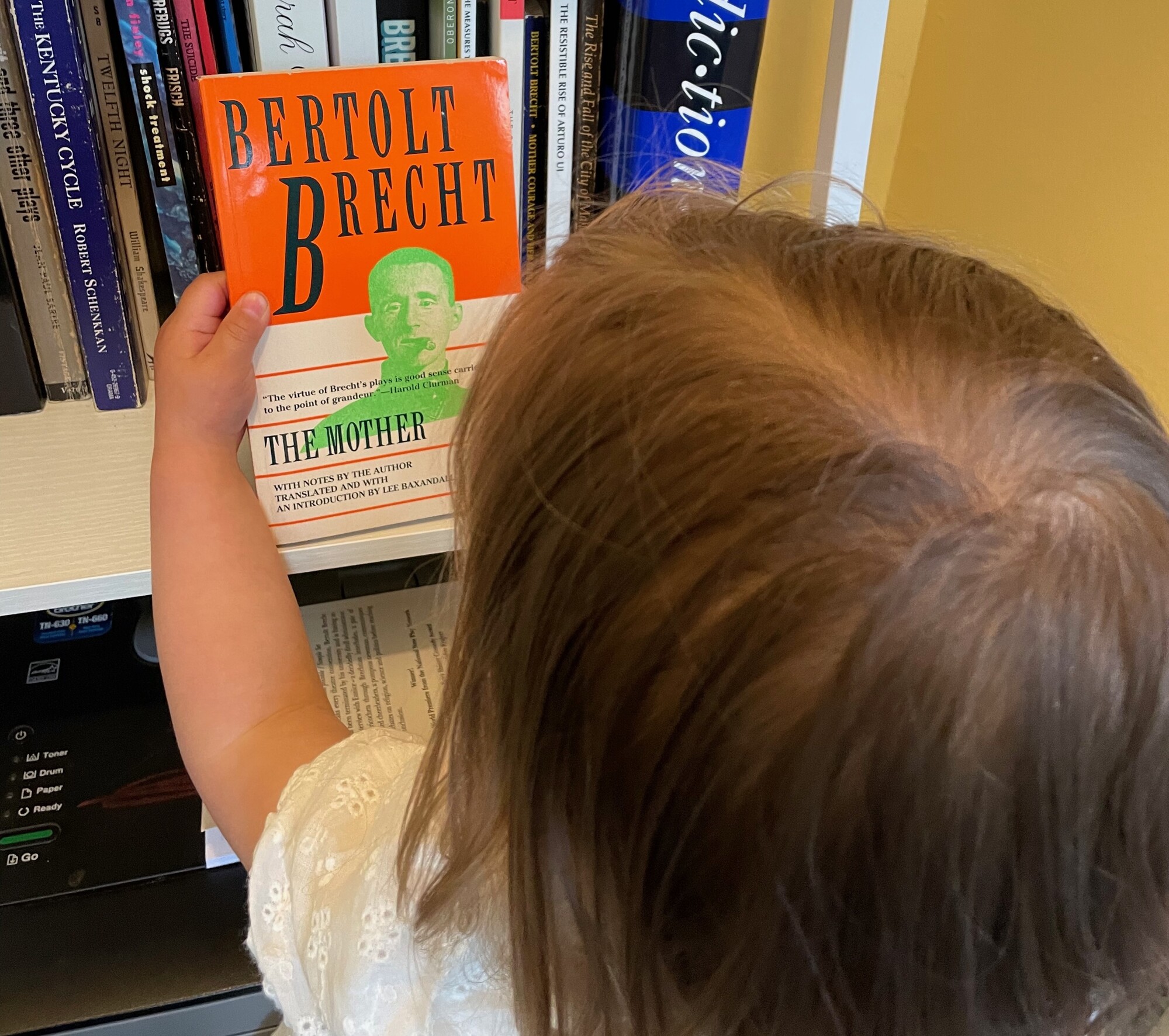 A child holds a copy of The Mother by Bertolt Brecht.