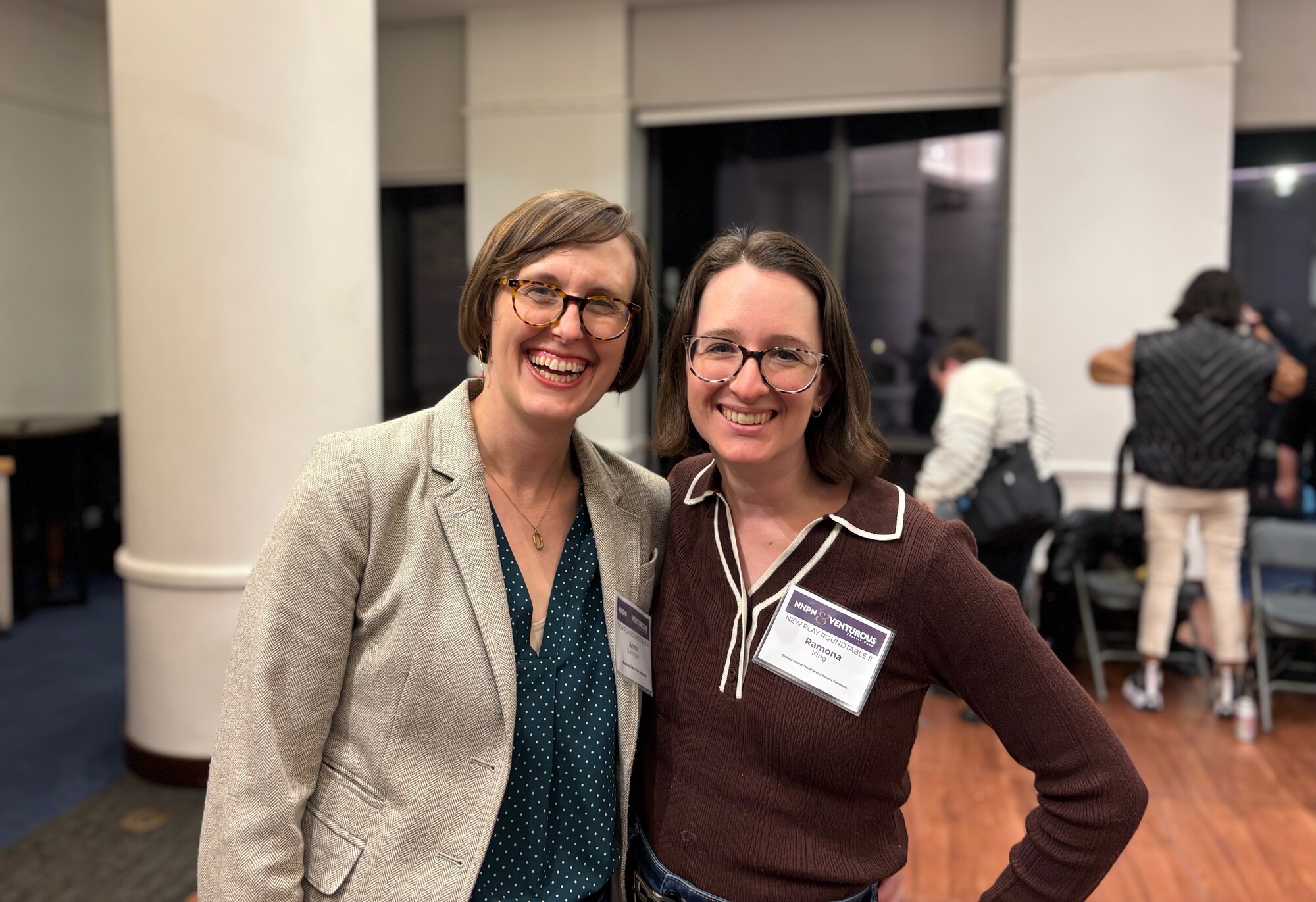 Two women pose for a photo at a conference.