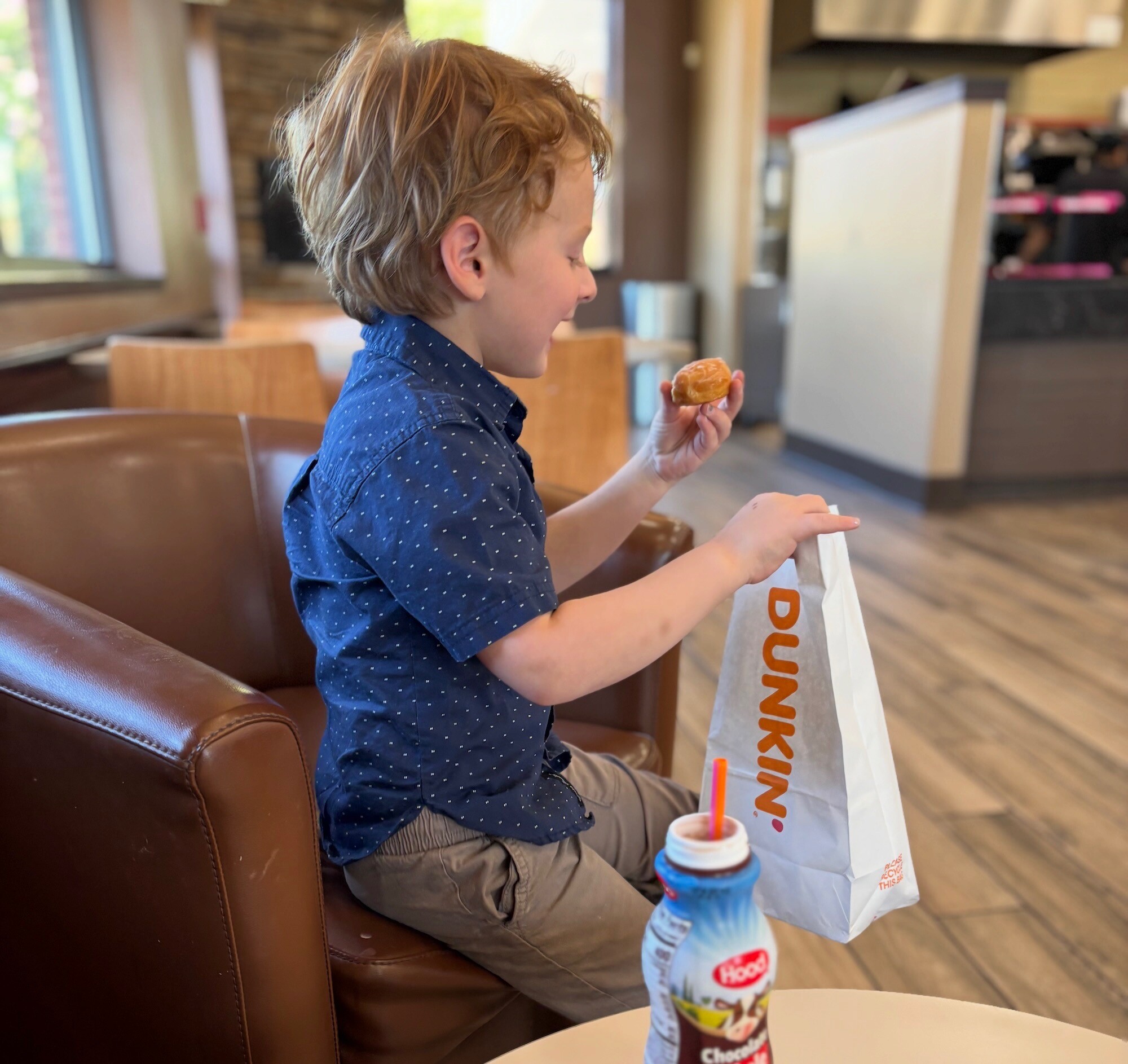 A child eating a treat from a Dunkin' bag.