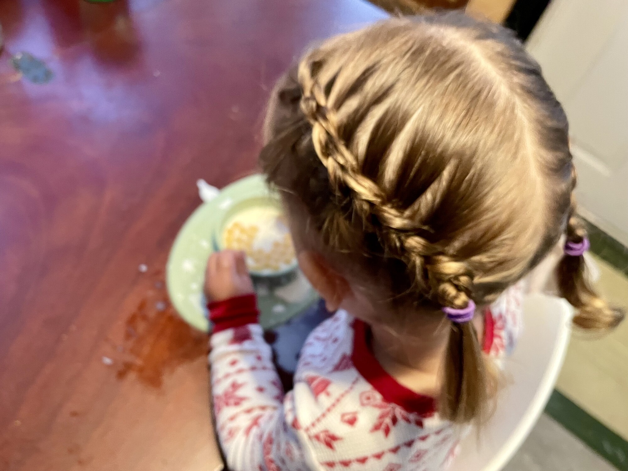 A child with french braids eats a meal.