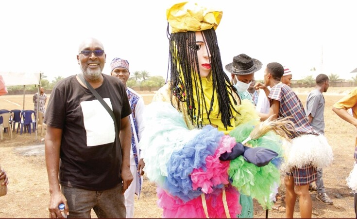 A man stands next to a life-sized puppet with long hair.