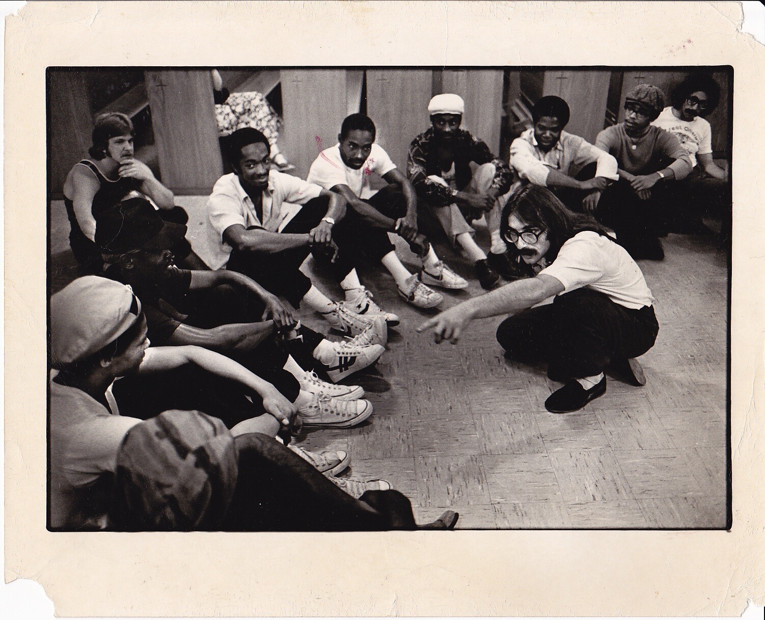 A man with long hair teaches a group of people.