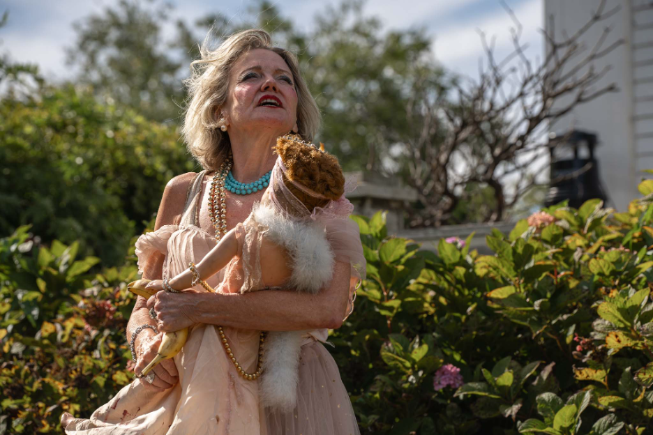 A woman holds a baby in an outdoor performance.