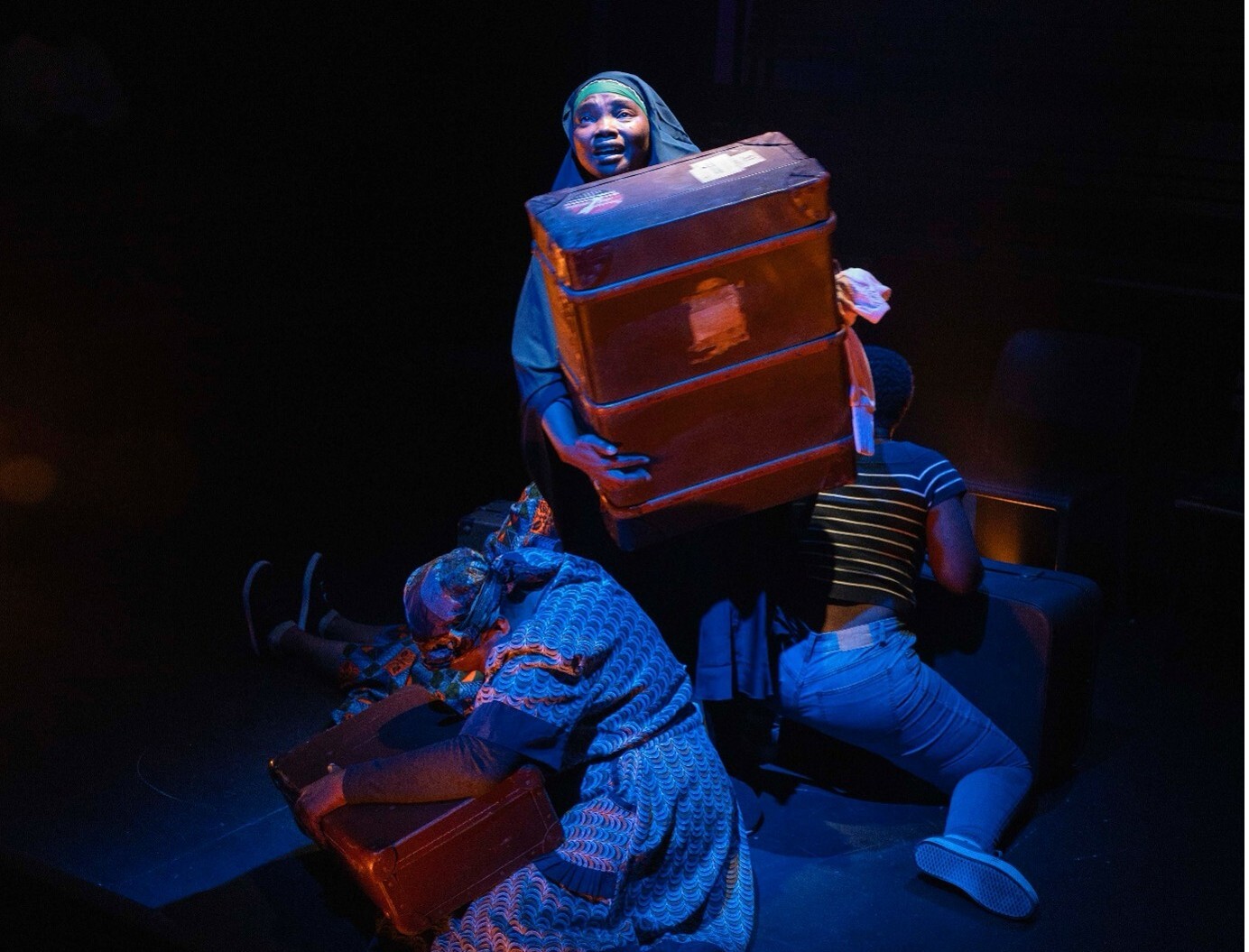 A performer holds a large suitcase onstage.